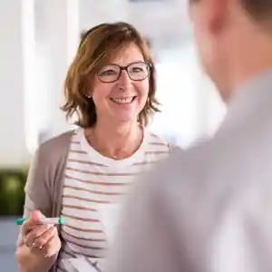 vrouw met bruin haar en bril lachend.